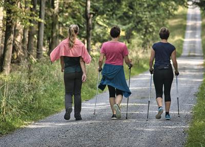 3 woman hiking along dirt wooded road