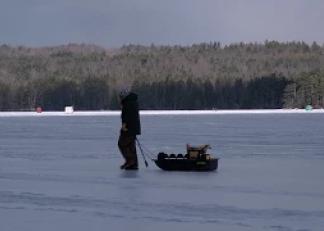 person walks across ice pulling a sled